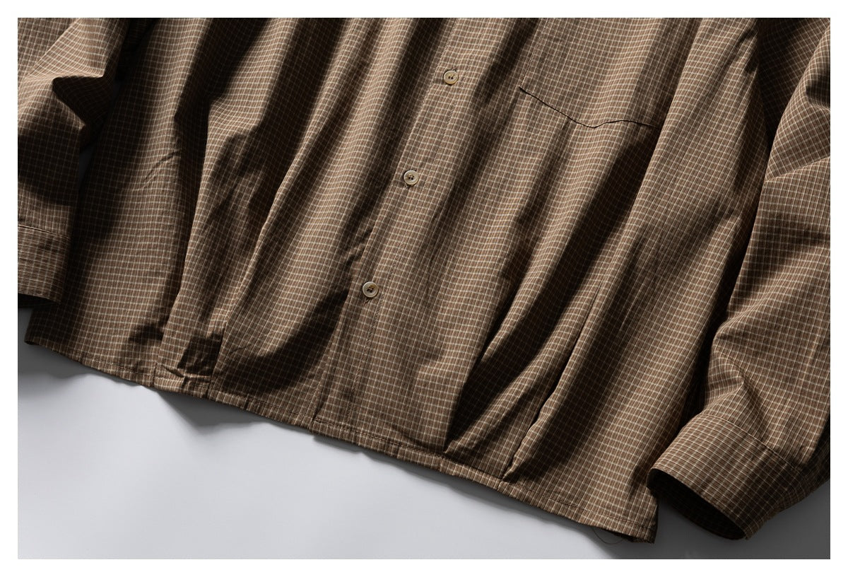 Cropped flat lay of a brown checked button-up shirt, showing its front placket, chest pocket, sleeves and cuffs.