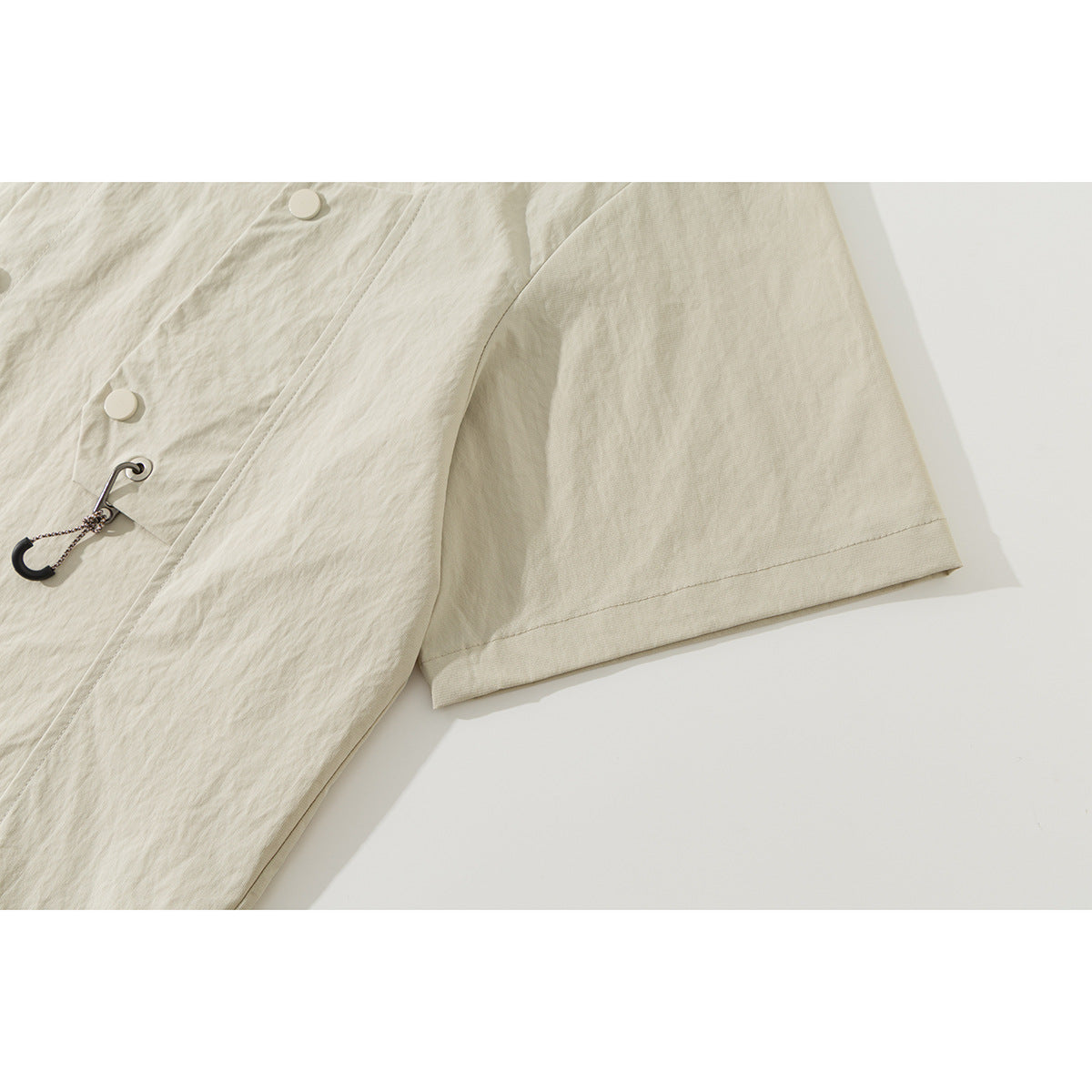 Close-up of the ivory shirt's short sleeve, front buttons, and small hook-and-cord accent.
