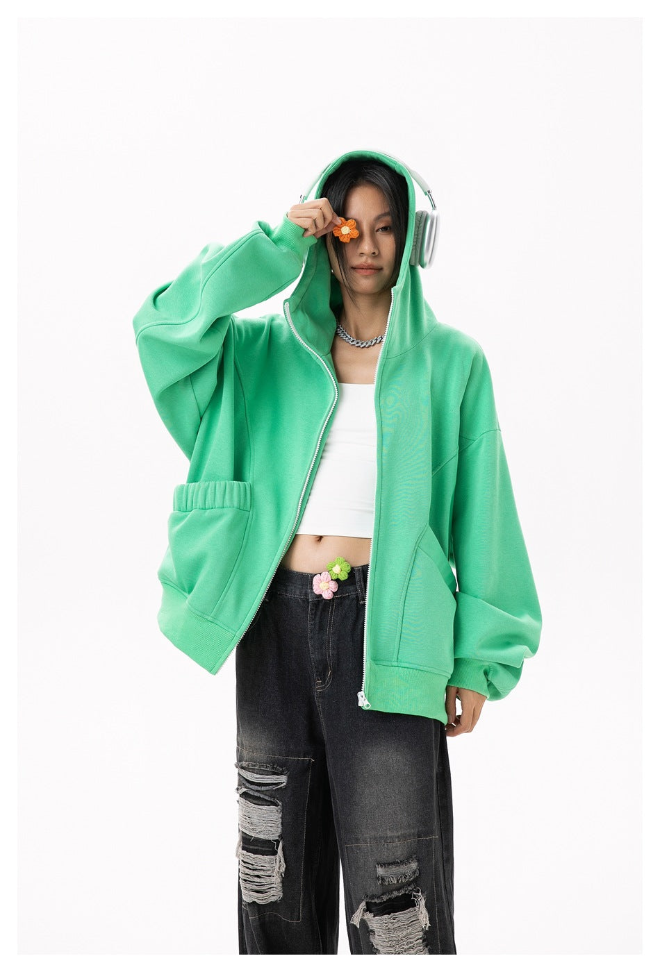 Model wears an open mint-green hooded zip hoodie with front pockets and flower appliqués, paired with black jeans.
