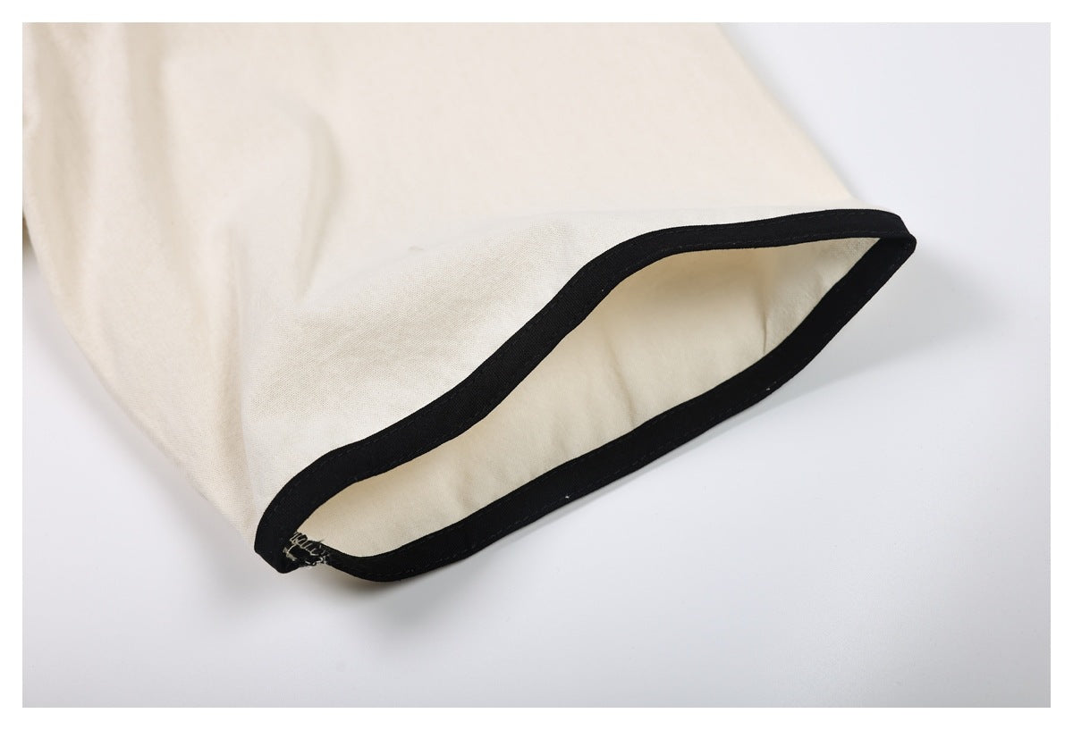 Close-up of a cream sleeve cuff edged with black binding.