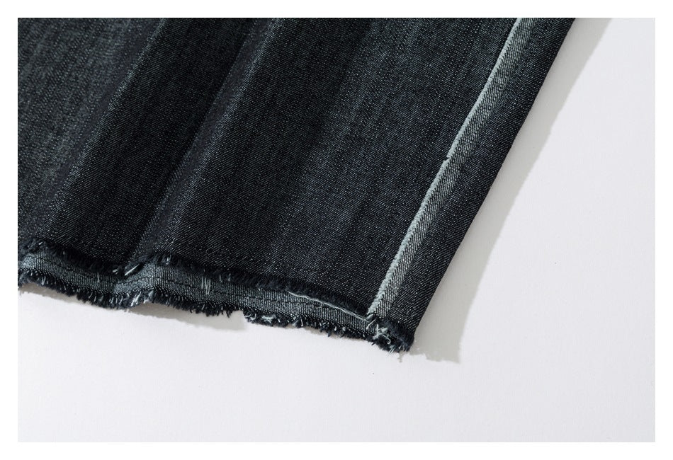 Close-up of a dark denim garment's raw, frayed hem and pale-edged side seam.