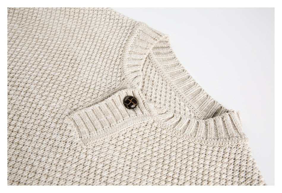 Close-up of a cream textured knit sweater's ribbed neckline and single-button placket.