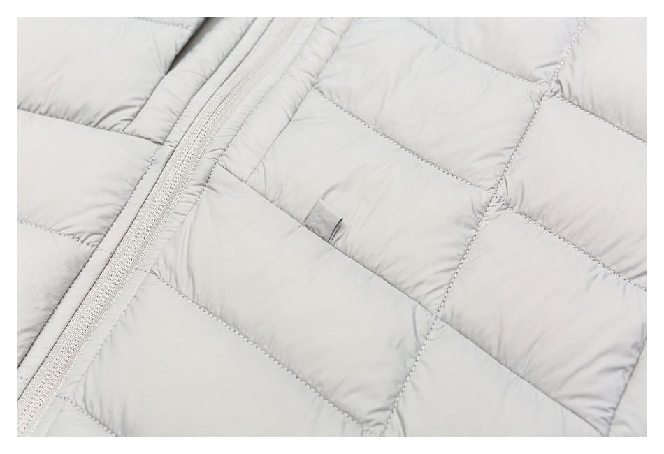 Close-up of light gray quilted jacket panels, zipper edge, and a small fabric tab.