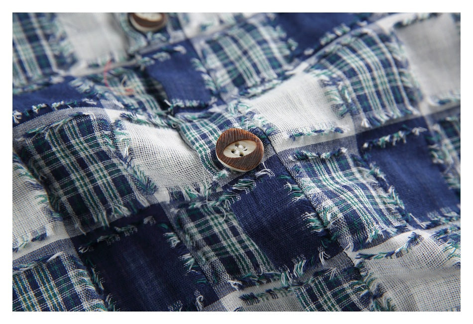 Macro view of a brown button, stitched seams and frayed blue, green and white plaid patches.