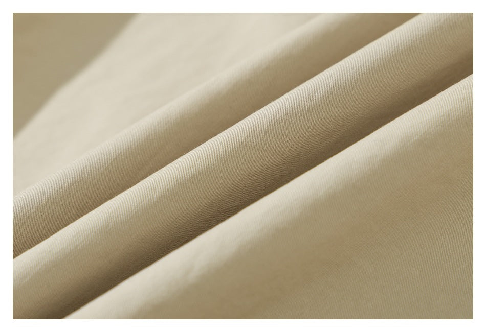 Close-up of light beige fabric in soft folds, showing its fine surface texture.
