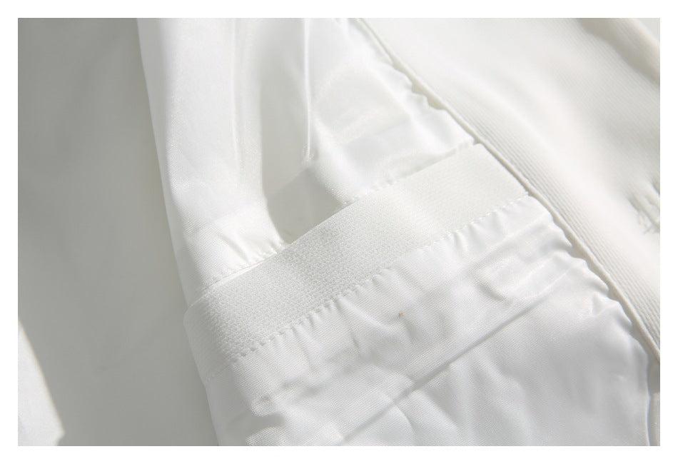 Close-up of a white garment's stitched band, panel, and seams.