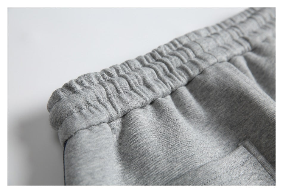 Close-up of the gathered elastic waistband and stitching on gray sweatpants.