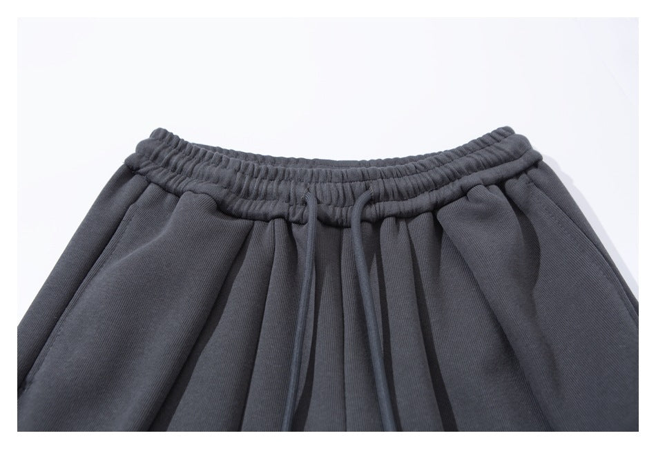 Close-up of charcoal jogger pants showing an elastic waistband, drawstrings, and front pleats.