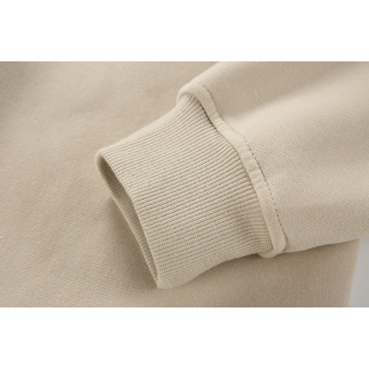 Close-up of a beige sweatshirt sleeve showing its ribbed cuff and stitched seam.