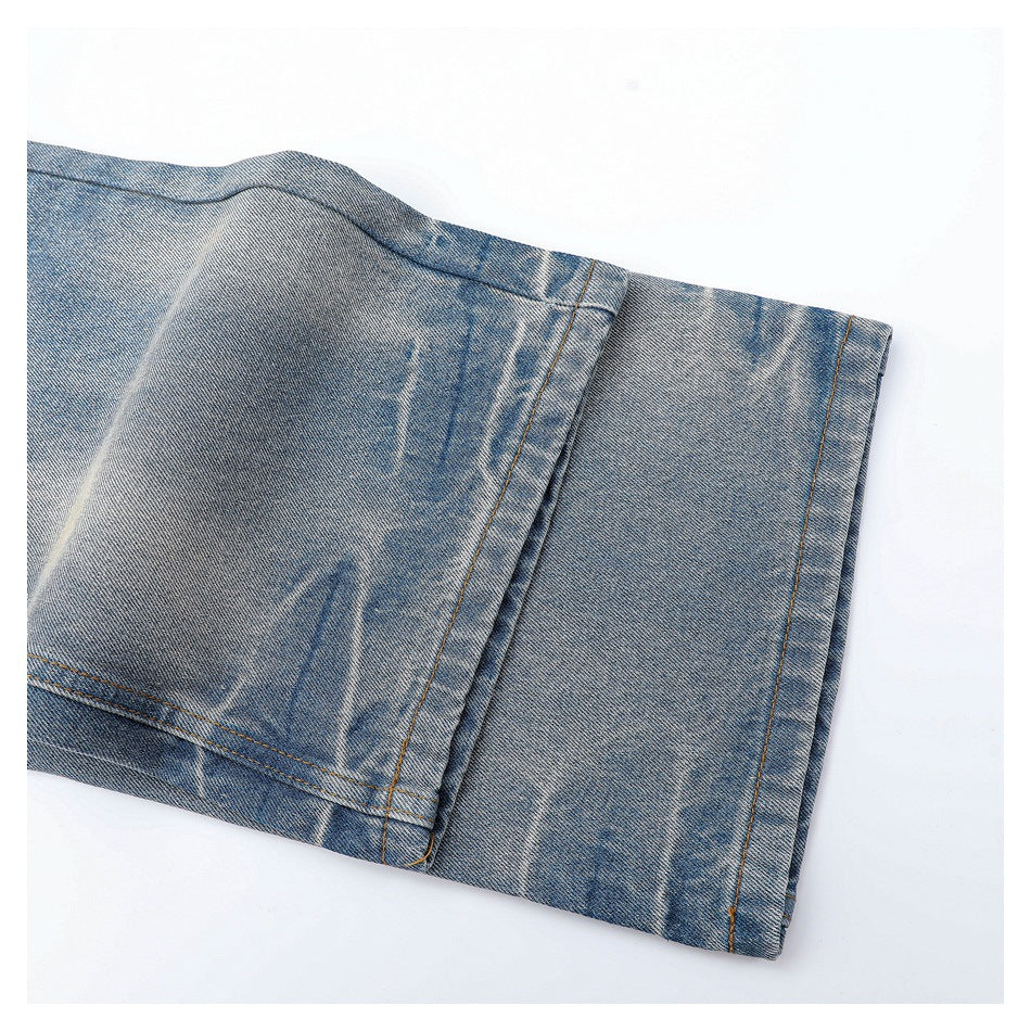 Close-up of a blue denim pant leg hem with orange stitching and faded marks.
