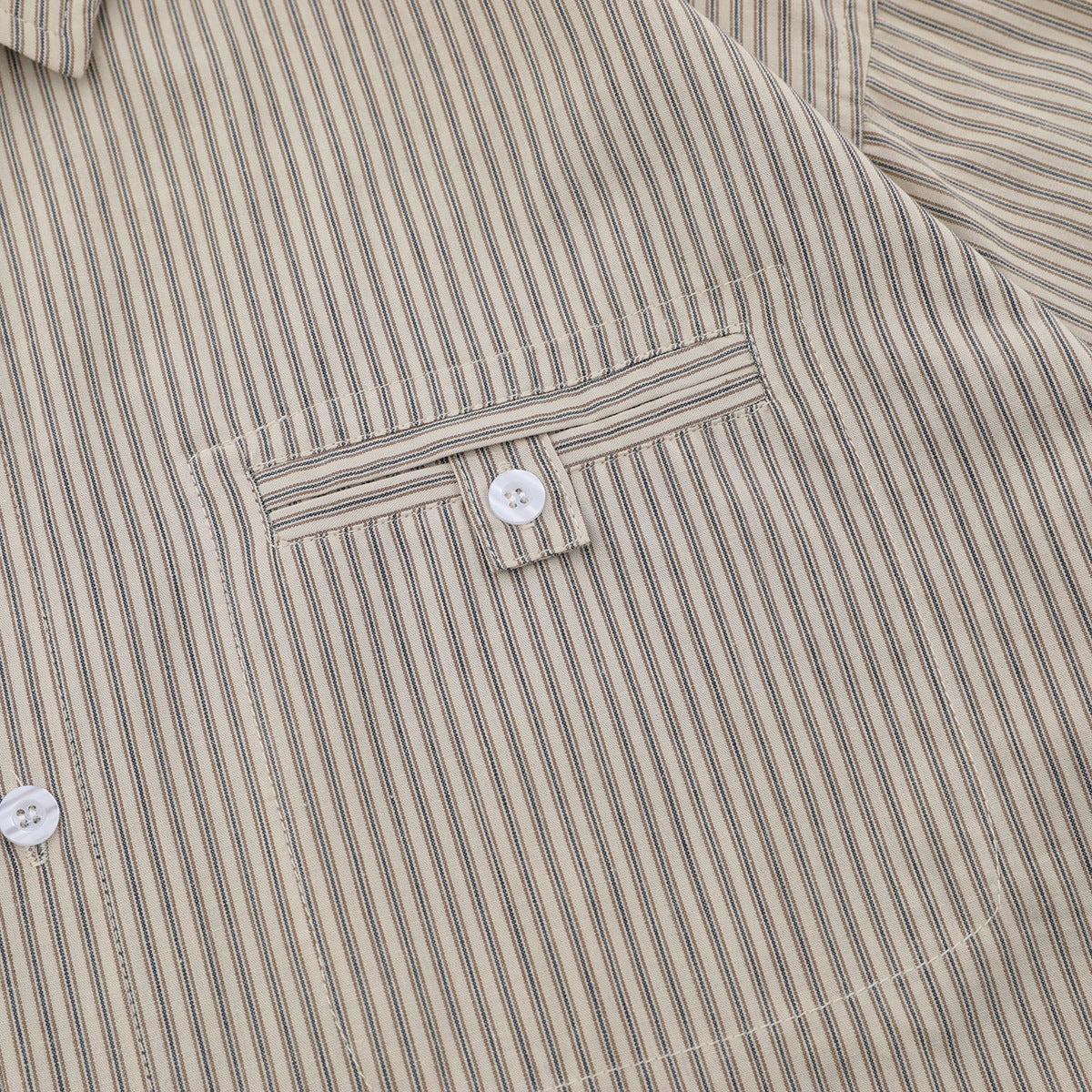 Close-up of a beige short-sleeve shirt with narrow dark stripes, showing its buttoned chest pocket.