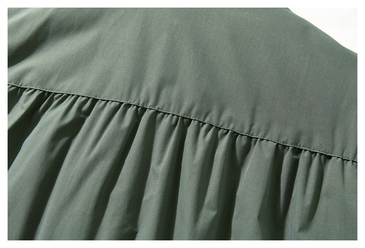 Close-up of the jacket's sage-green back yoke seam and gathered fabric below it.