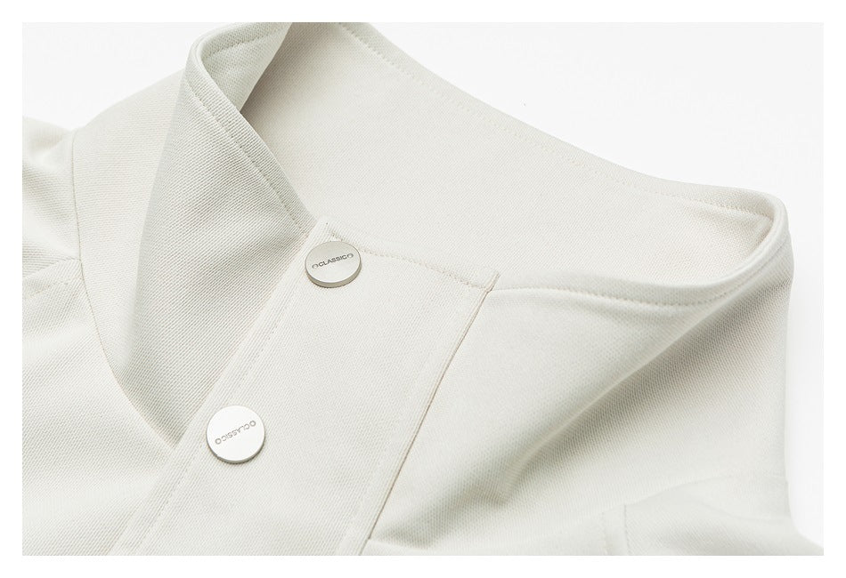 Close-up of an off-white jacket's stand collar and front placket with two round metal buttons.