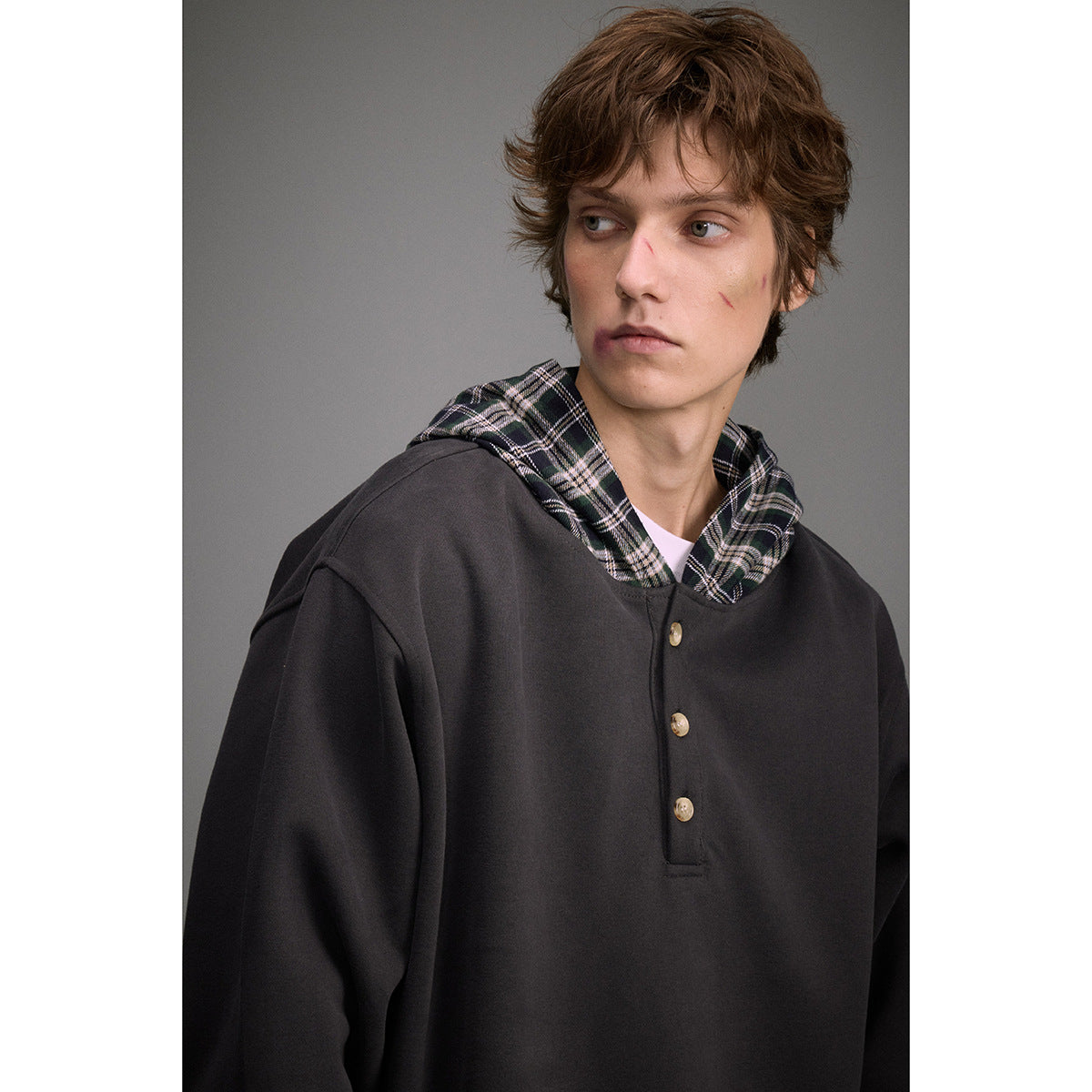 Man wearing a charcoal pullover with a three-button front and black plaid-lined hood.