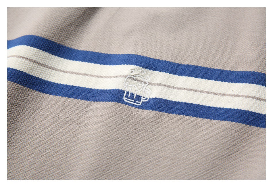 Close-up of a small white embroidered emblem on the T-shirt’s blue and ivory stripe.