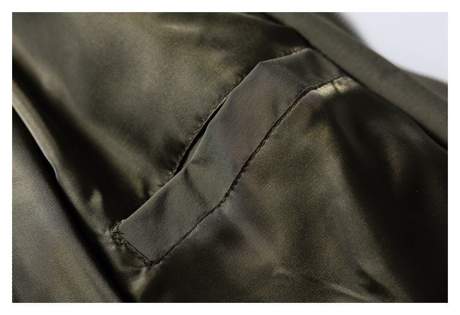 Close-up of a curved seam and fabric panel on an olive green jacket.
