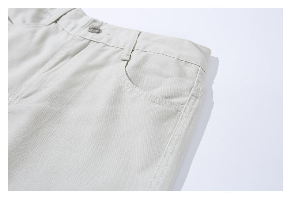 Close-up of ivory trousers showing the front button, belt loop, and curved pocket.