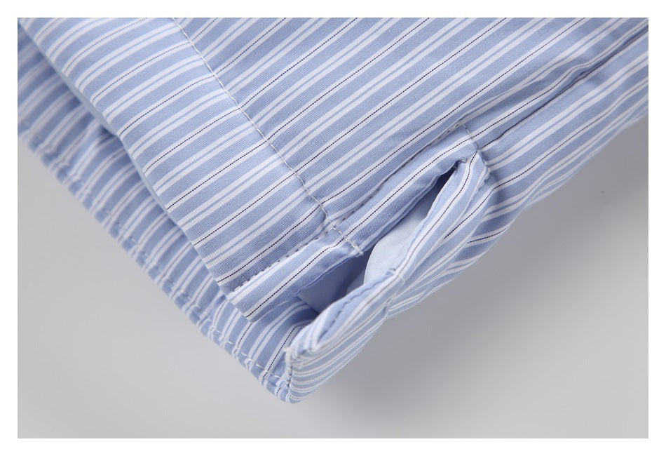 Close-up of a stitched edge and opening on a pale blue and white striped shirt.