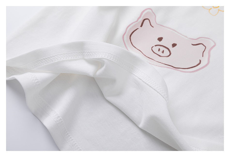 Close-up of the white T-shirt’s stitched hem and pastel pig illustration.