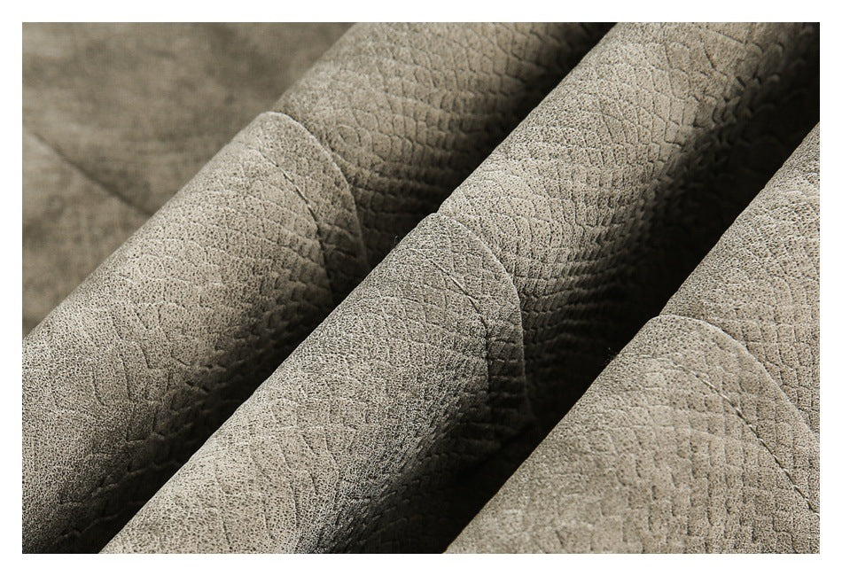 Close-up of folded taupe jacket fabric showing a raised reptile-like texture and stitched seams.