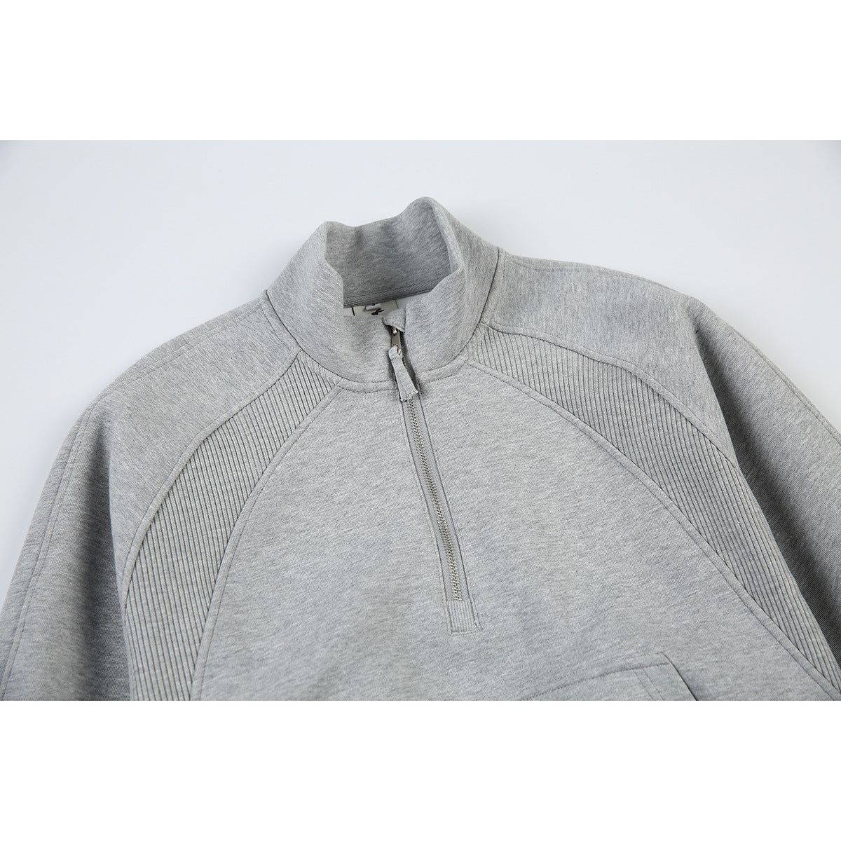 Close-up of a heather-gray pullover with a short stand collar, quarter zip, and ribbed front panels.
