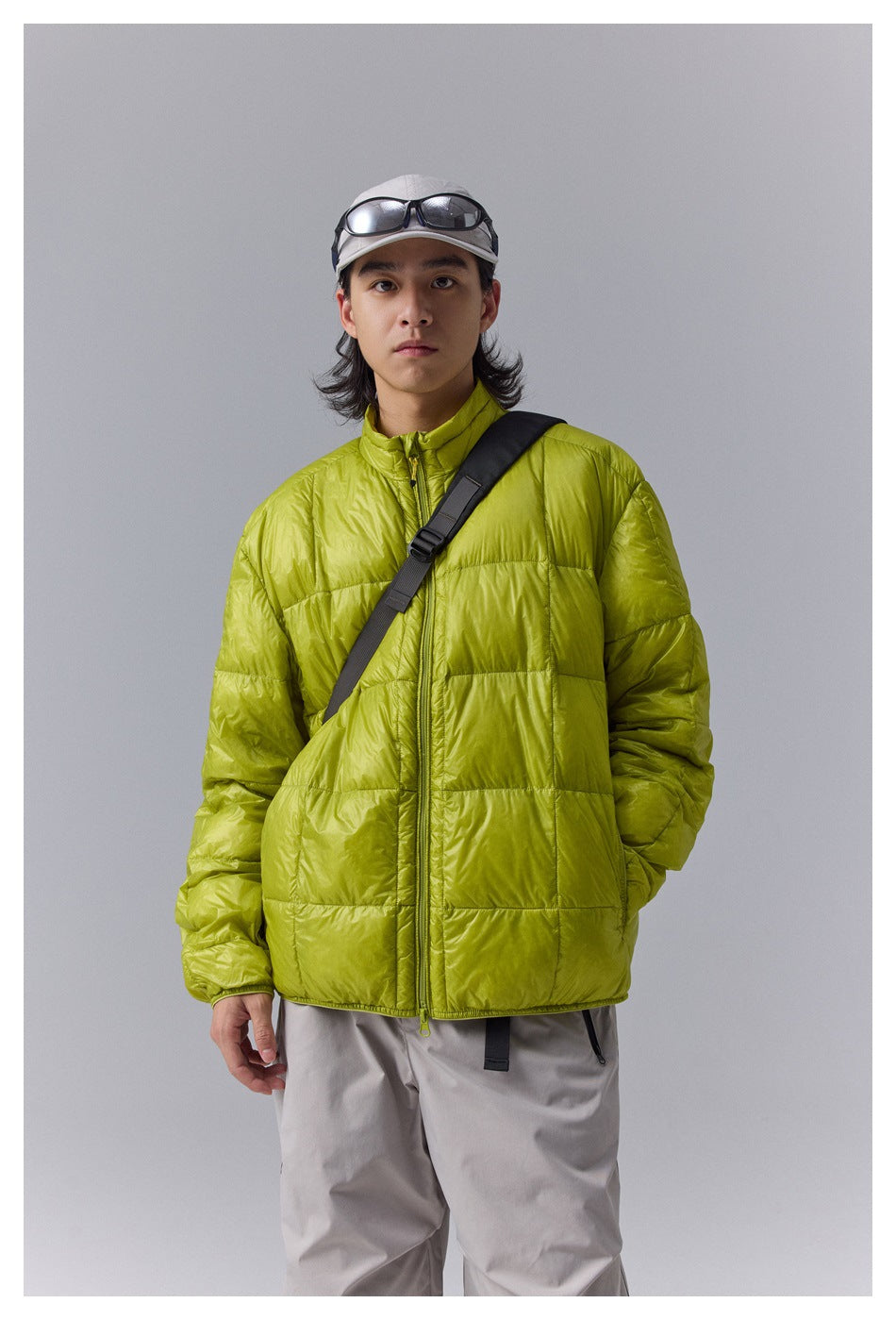 Model wearing a lime-green quilted zip jacket with a high collar and black crossbody strap, shown from the front.