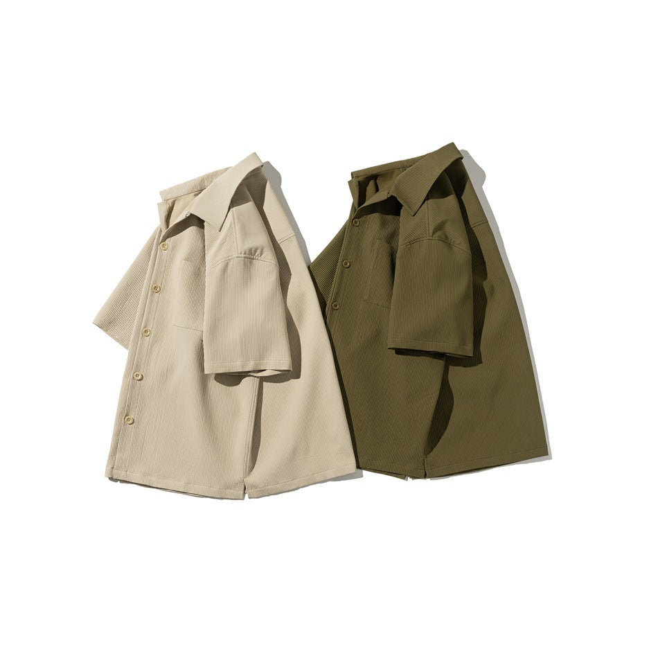 Angled views of beige and olive short-sleeve button-up shirts with collars, buttons, and chest pockets.