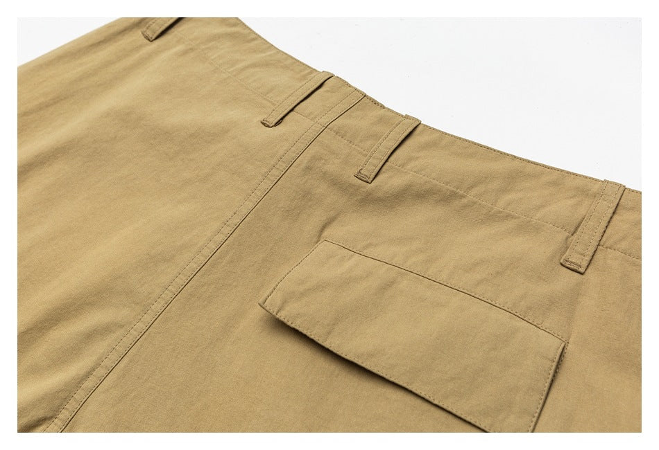 Close-up of tan trousers showing a rectangular flap pocket on the back.