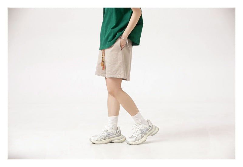 Side view of a model wearing light beige drawstring shorts with a green T-shirt.