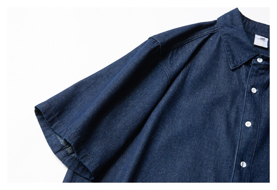 Close-up of a dark indigo shirt showing its short sleeve, shoulder seam, pointed collar and white-button placket.