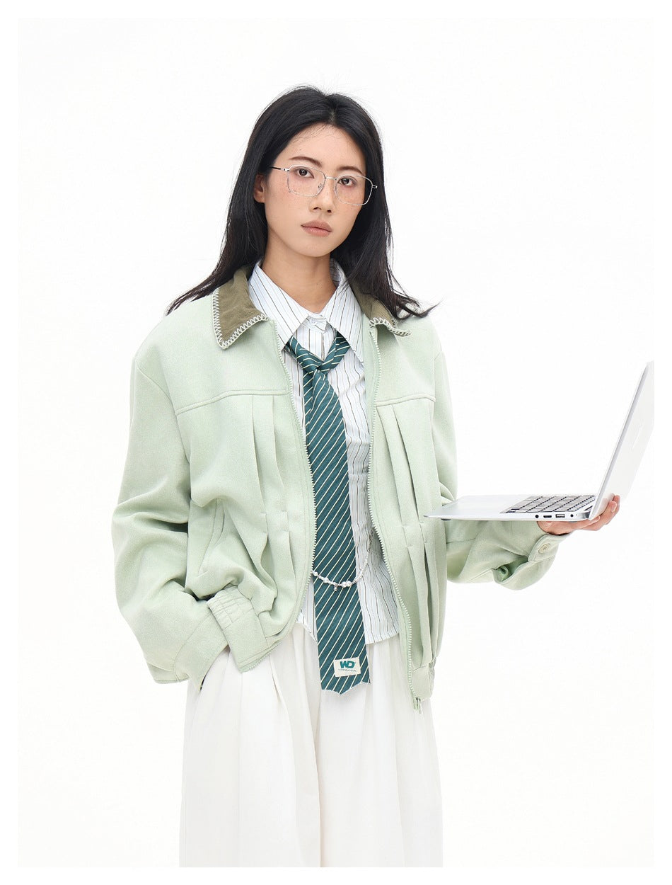 Model wearing a pale mint zip-front jacket with a brown stitched collar, striped shirt, and tie.