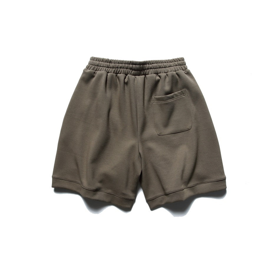 Back view of taupe shorts with an elastic waistband, a patch pocket, and wide hems.