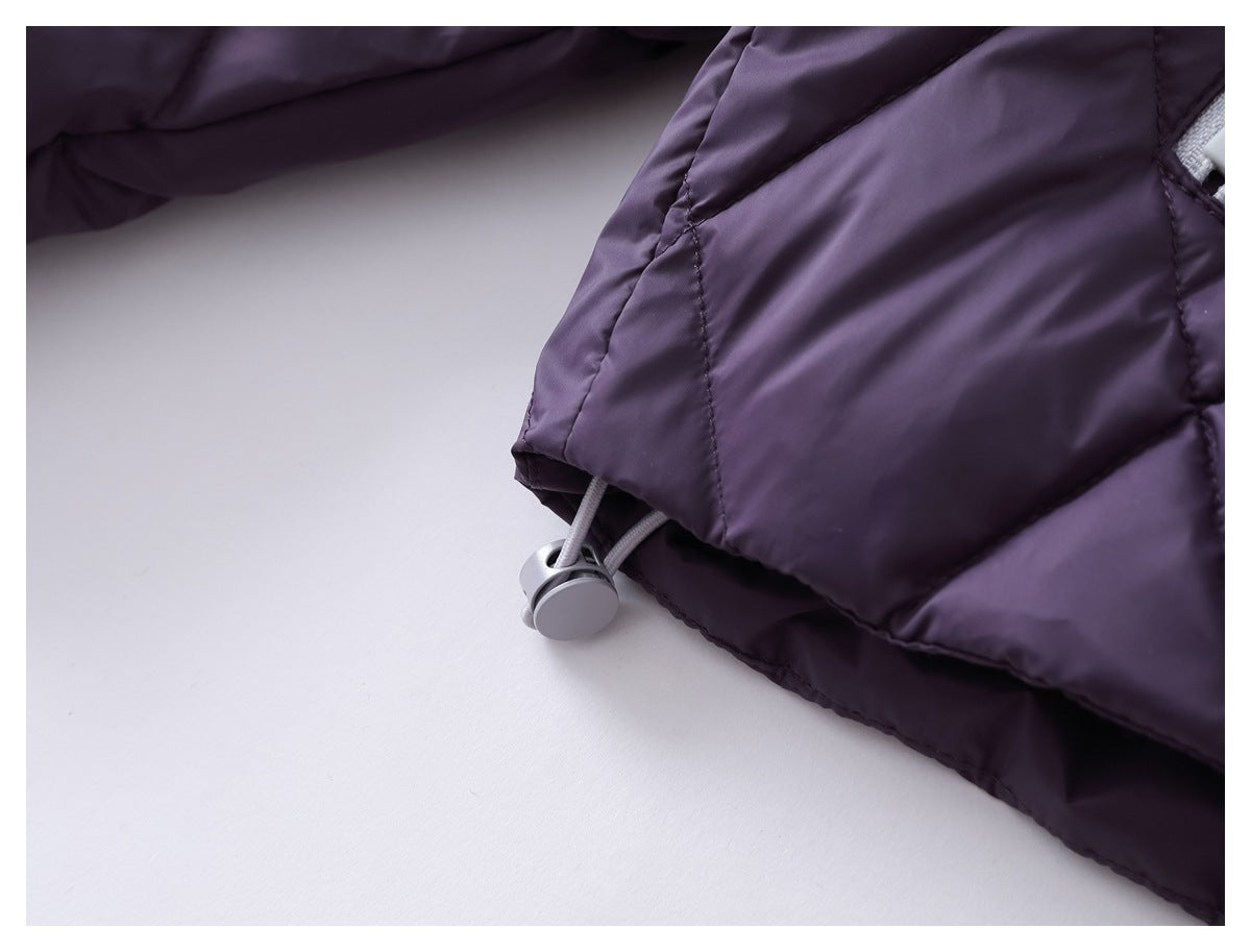 Close-up of a gray drawcord toggle at the hem of a dark purple quilted garment.