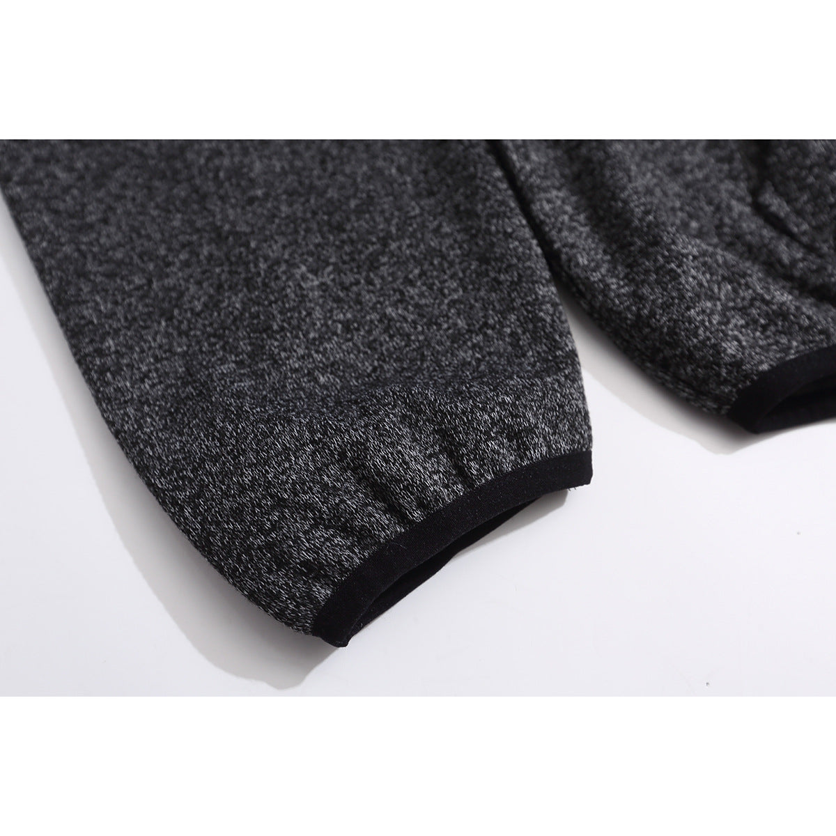 Close-up of a charcoal marled hoodie sleeve ending in a black-trimmed cuff.