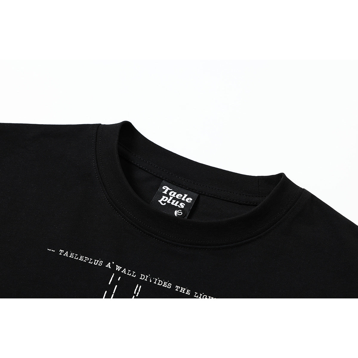 Close-up of a black T-shirt collar and upper chest, with a partially visible white text print and neck label.