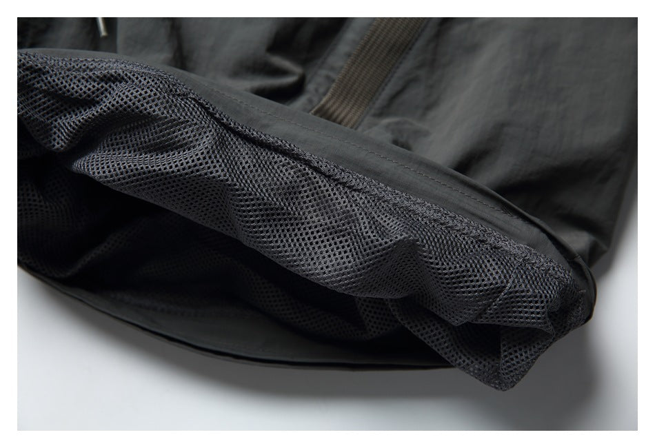 Close-up of dark charcoal garment with black mesh lining and stitched edging.