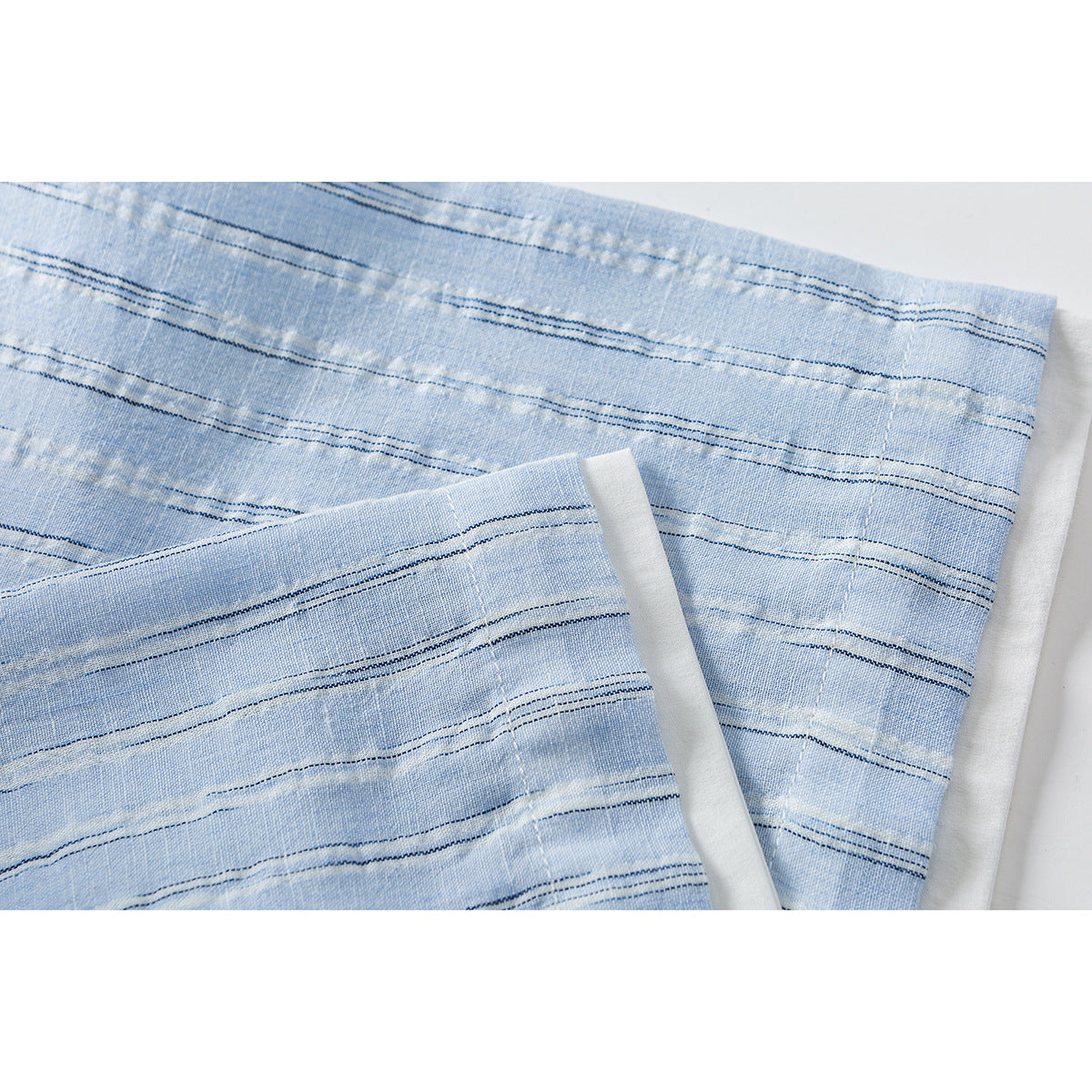 Close-up of a light blue striped shirt sleeve cuff with its folded edge and stitching.