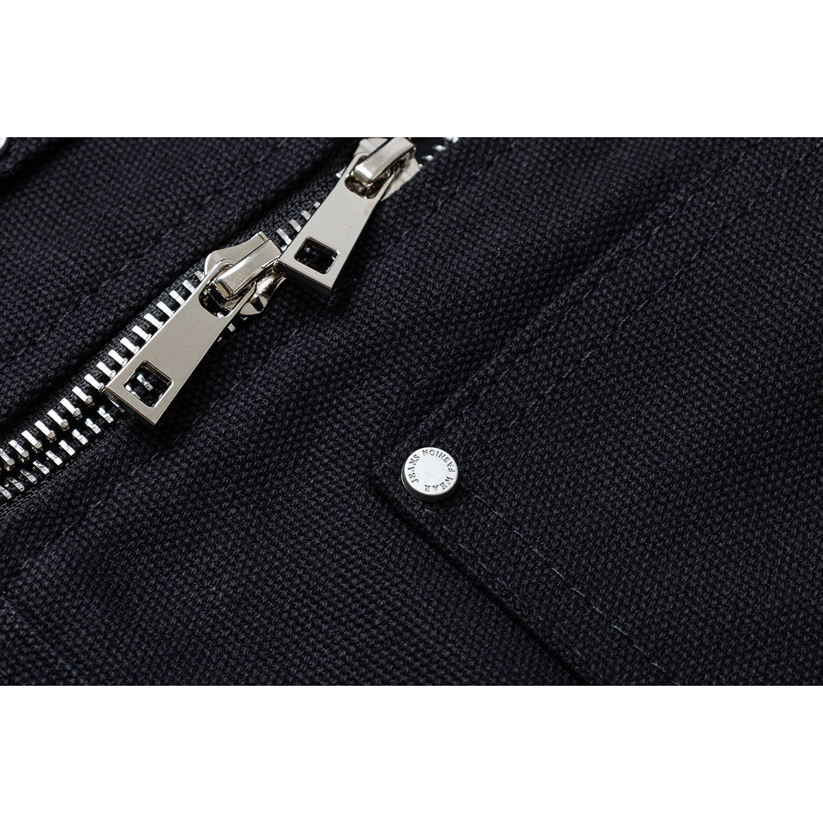 Close-up of a metal zipper and snap on dark textured jacket fabric.