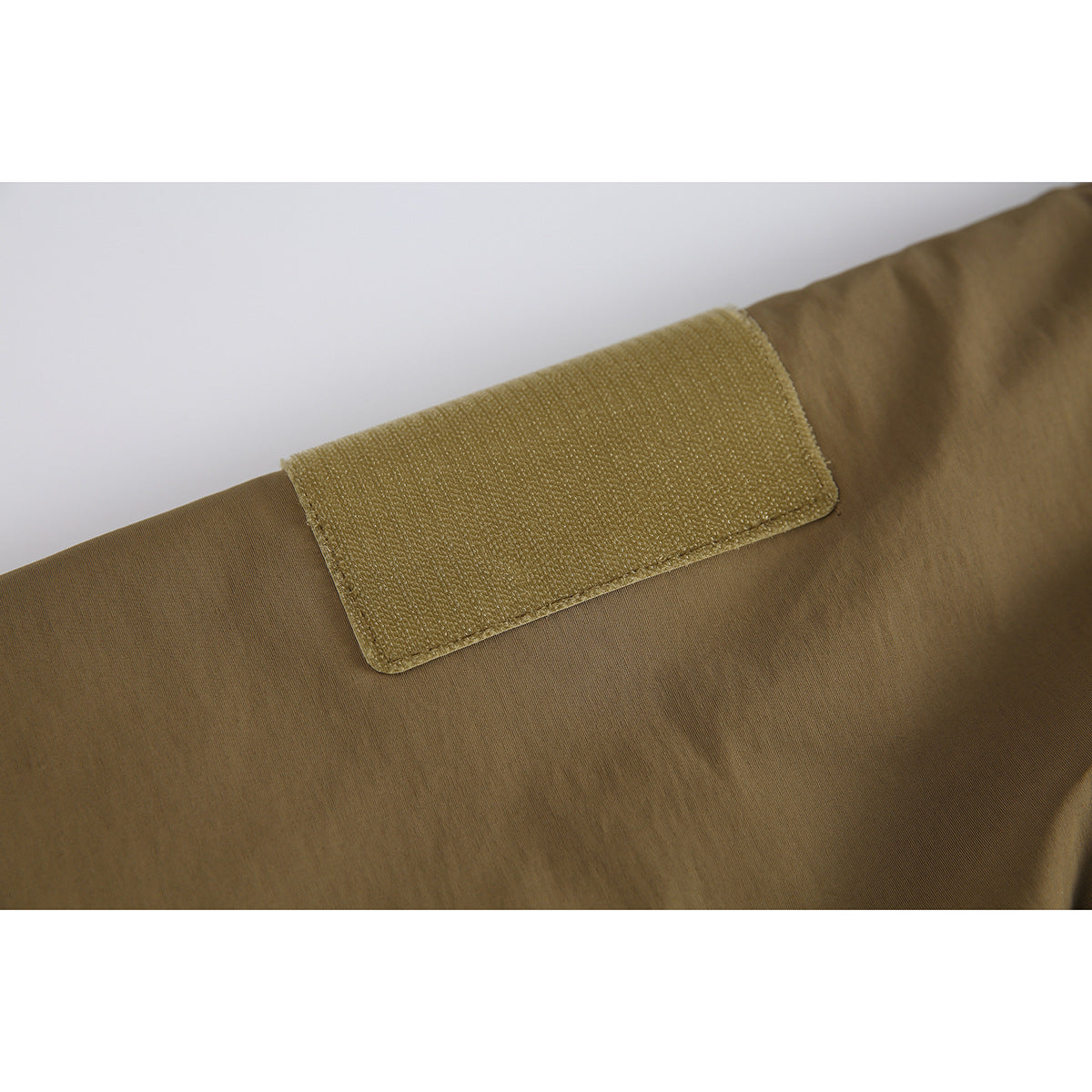 Close-up of a rectangular hook-and-loop patch on the sleeve of a khaki jacket.