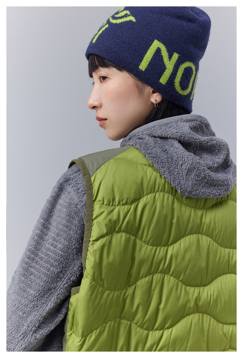 Close-up of the back and shoulder of a lime-green wave-quilted vest over gray fleece.
