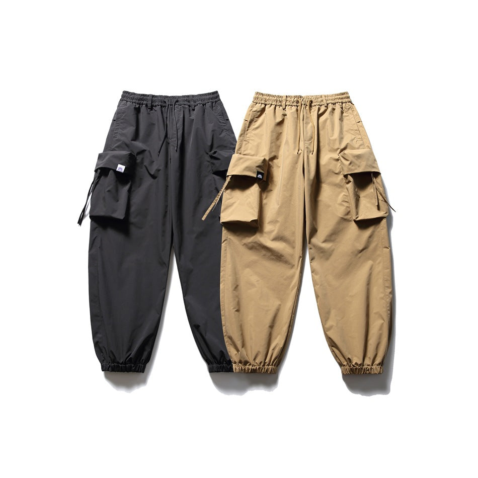 Black and tan cargo jogger pants displayed side by side, each with an elastic waist and large cargo pockets.