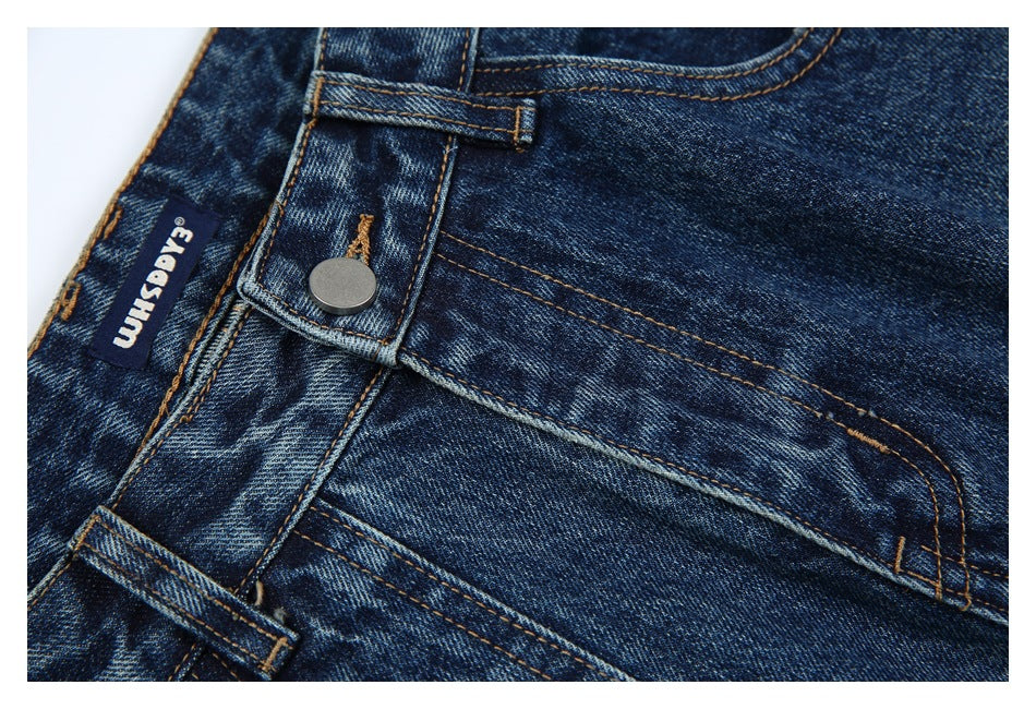 Close-up of dark blue faded jeans showing the waistband, button, belt loops, pocket stitching and a sewn label.