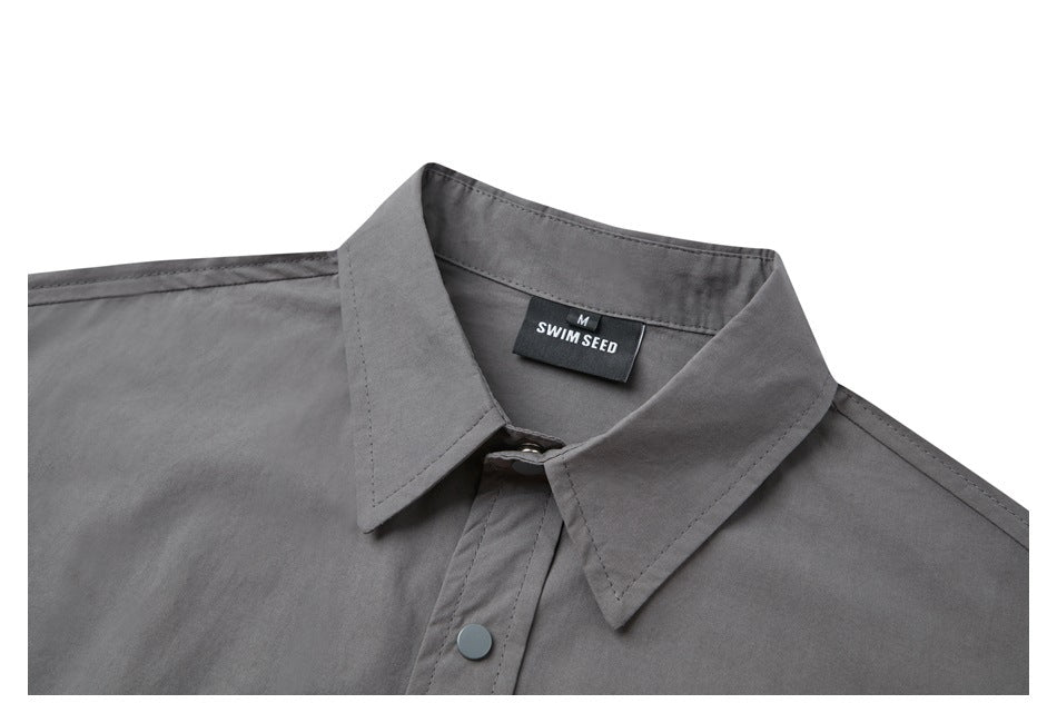 Close-up of a gray button-front shirt collar with a black SWIM SEED size M neck label.