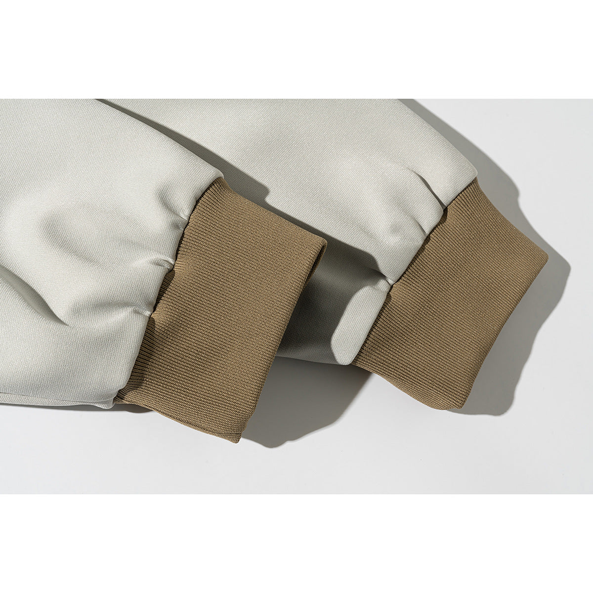 Close-up of cream jacket sleeves ending in wide tan ribbed cuffs.