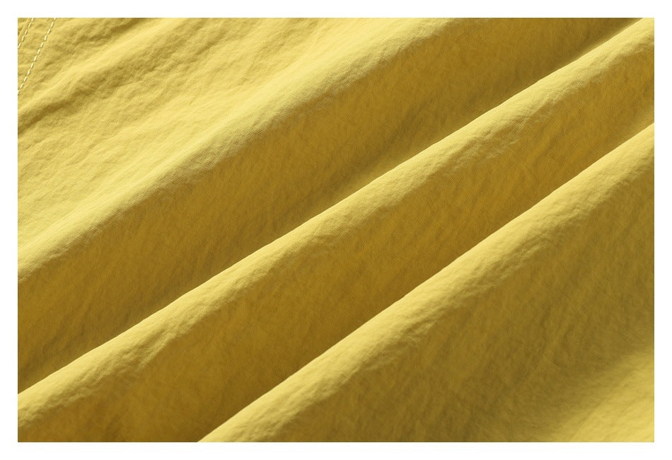 Close-up of mustard-yellow fabric draped in folds, showing its fine surface texture.