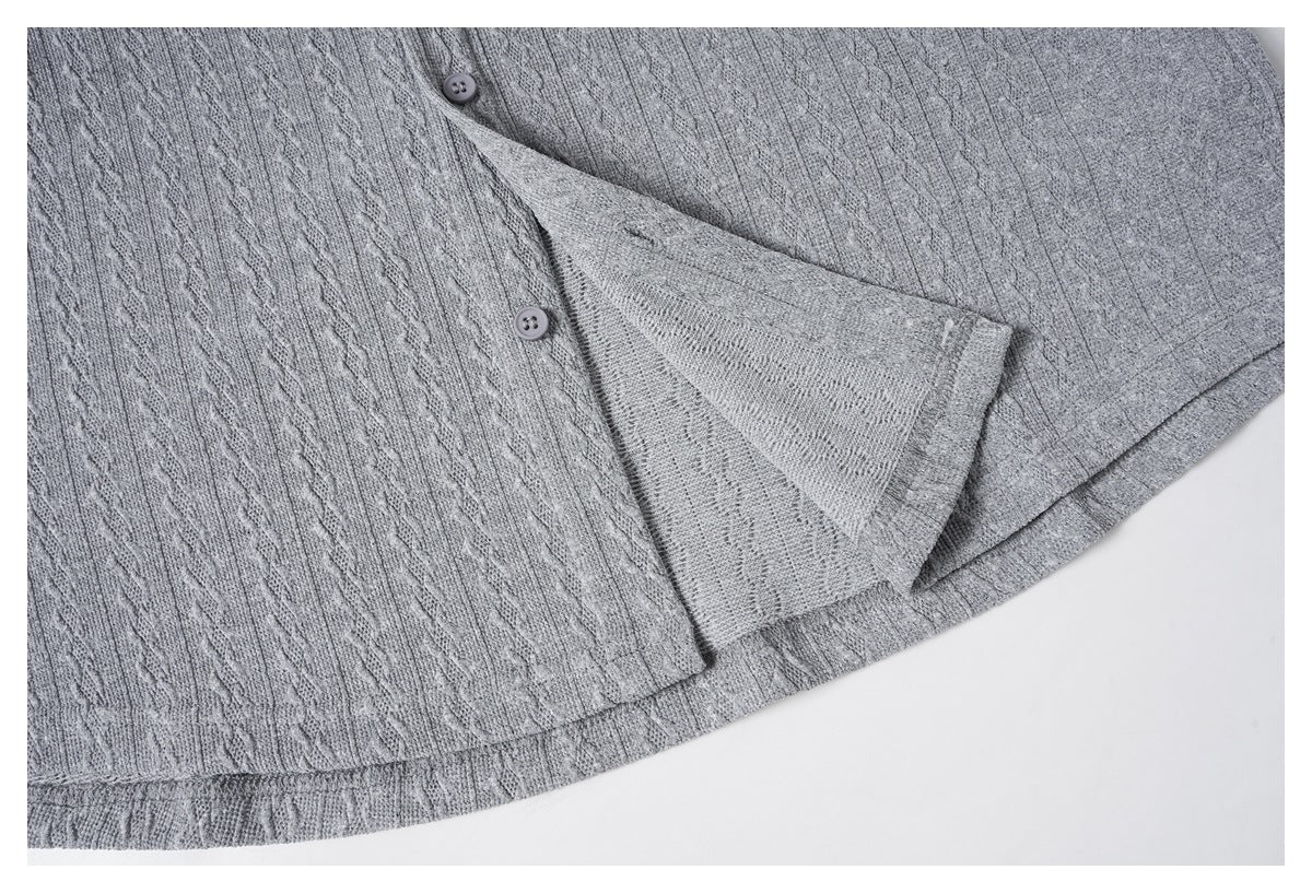 Close-up of a gray cable-knit garment showing two buttons and a folded edge.