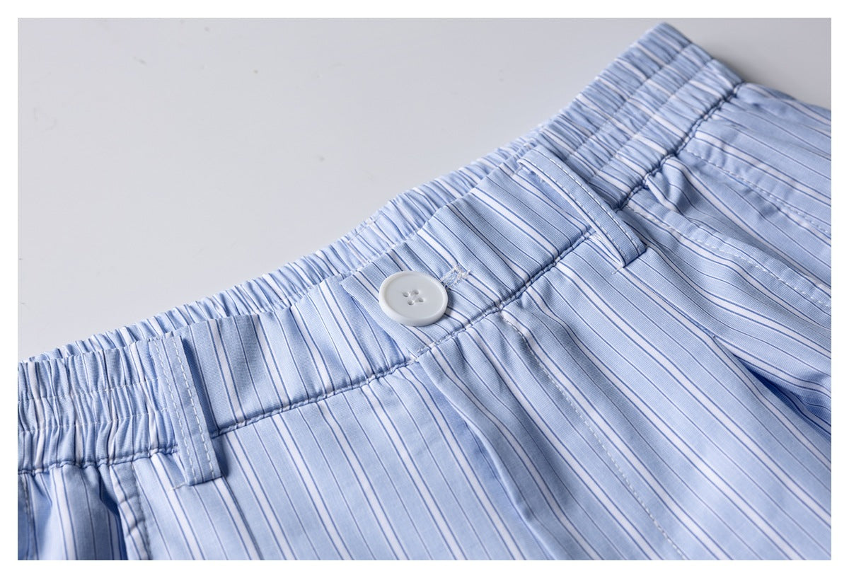 Close-up of the light blue pinstriped shorts' waistband, white button, belt loops and gathered elastic section.