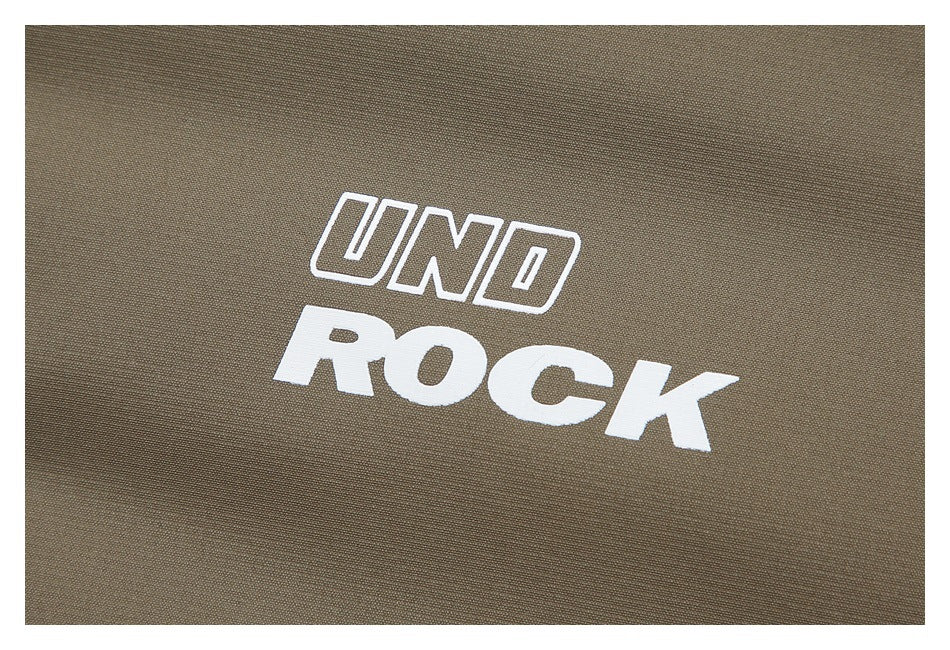 White outlined and solid lettering reading “UND ROCK” printed on taupe-brown fabric.