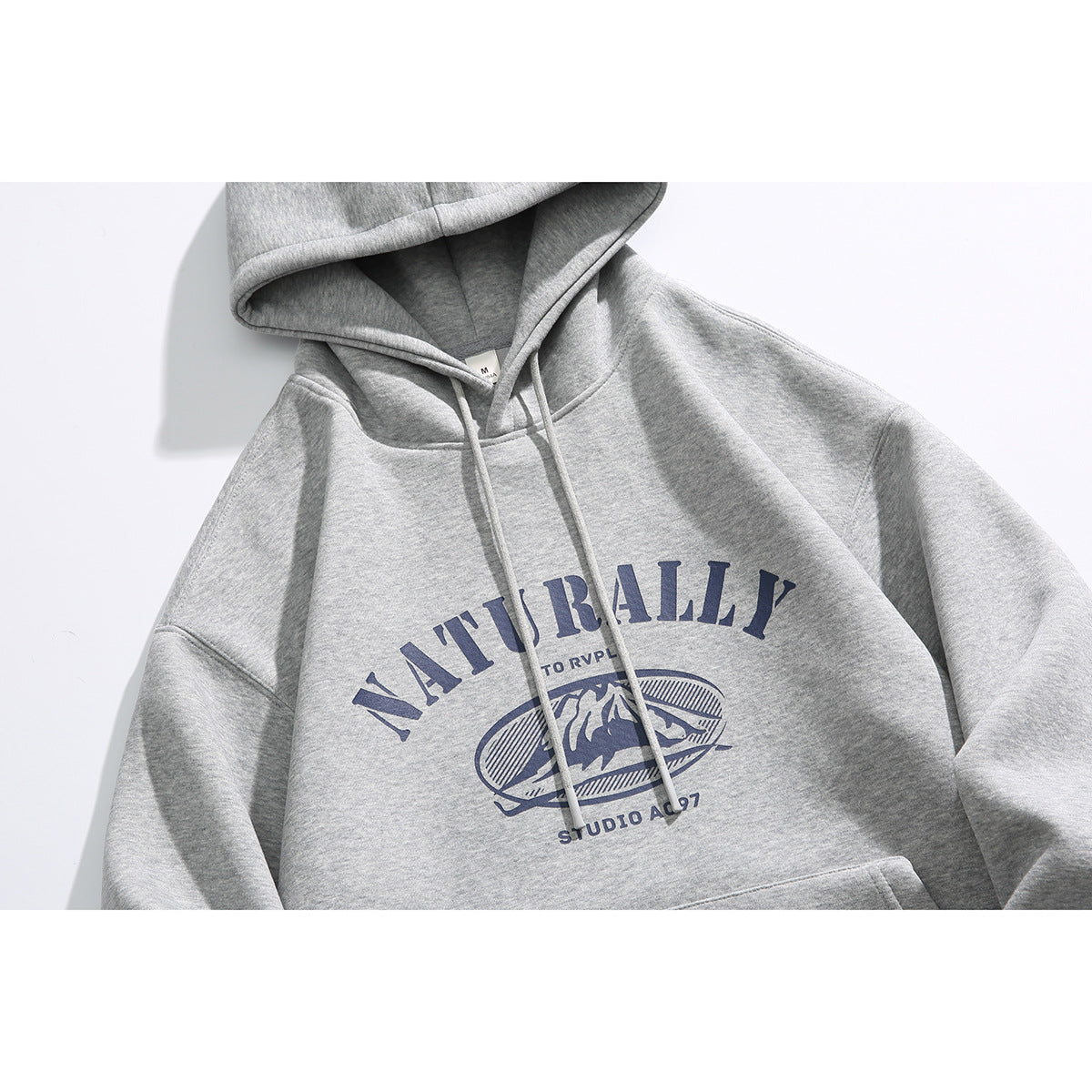 Close-up of a heather gray pullover hoodie with drawstrings and a navy mountain graphic with English lettering.