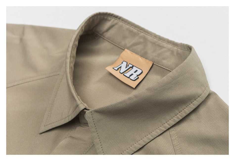 Close-up of a taupe shirt collar and inner neck label marked “NB.”